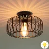 A close-up of a retro-style ceiling lamp with a wire cage and an Edison-style LED bulb, casting light rays on the ceiling. Náhľad obrázku produktu