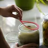 A person is holding a red rubber seal over a glass jar filled with a light-colored liquid. Anteprima dell’immagine prodotto