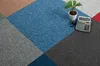 A close-up view of carpet tiles arranged in a geometric pattern, with a calculator and a small potted plant on top. Produktbild-Vorschau
