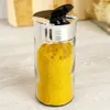 A close-up shot of a spice jar filled with yellow powder, placed on a light-colored wooden surface. Produktbild-Vorschau