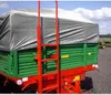 A close-up view of a green and red agricultural trailer covered with a gray tarp. Produktbild-Vorschau