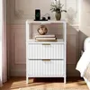 A white nightstand with two drawers and an open shelf, placed in a bedroom setting. Náhled obrázku produktu