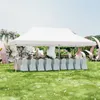 An outdoor event setup with a white tent, tables, and chairs, decorated with flowers and large decorative elements. Produktbild-Vorschau