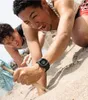 Two young men playing on a sandy beach, one wearing a black digital watch. Podgląd zdjęcia produktu