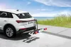 A white car with a bike rack attached is parked on a paved area near a beach. Podgląd zdjęcia produktu