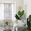 A living room scene with a macrame curtain, sofa, plants, and a coffee table. Produktbild-Vorschau