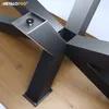 A close-up view of a black metal table base with a star-shaped design, resting on a wooden floor. Produktbild-Vorschau