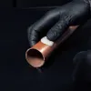 A gloved hand is applying a putty-like substance to a copper pipe. Anteprima dell’immagine prodotto