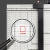 A close-up view of a paper cutter with a magnifying glass highlighting a 1x1cm measurement. Produktbild-Vorschau