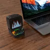 A black Divoom Ditoo Pro Bluetooth speaker is placed on a wooden table next to an open laptop. Produktbild-Vorschau