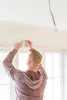 A person is using a laser level to mark a line on a wall above a window. Produktbild-Vorschau
