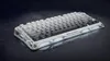 A 75% wireless mechanical gaming keyboard with a gradient white and gray keycap design and a unique, sculpted white frame, displayed on a dark, reflective surface. Produktbild-Vorschau