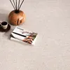 A close-up view of a rug with decorative items on it, including a book, glasses, a cup of coffee, and a diffuser. Produktbild-Vorschau
