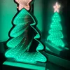 A Christmas tree-shaped LED light with an infinity mirror effect is shown in front of a mirror, reflecting its image. Produktbild-Vorschau