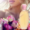 A woman's décolletage and mouth are visible, holding a bouquet of roses and a bottle of perfume. Anteprima dell’immagine prodotto
