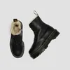 A pair of black Dr. Martens boots with fur lining, shown from a top-down diagonal angle against a white background. Anteprima dell’immagine prodotto