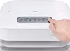 A hand is pressing a button on the control panel of a white appliance. Produktbild-Vorschau
