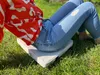 A person sitting on a grassy area with a heated seat cushion. Náhled obrázku produktu