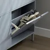A close-up shot of a gray shoe cabinet with one of its flip-out drawers open, revealing a pair of beige and black sneakers inside. Náhľad obrázku produktu