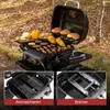 A portable gas grill is set up outdoors in a wooded area with fallen leaves on the ground. The grill is in use, with food cooking on the grates and buns warming on a top rack. Two inset images show close-ups of the grill's internal components. Produktbild-Vorschau