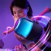 A woman is holding a Bluetooth speaker with colorful lights, surrounded by light trails, suggesting a party or music experience. Náhled obrázku produktu