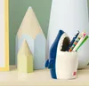 A shark-shaped pen holder filled with colorful pens sits on a shelf next to decorative pencil-shaped objects. Anteprima dell’immagine prodotto