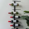 A metal wine rack holding several bottles of wine, mounted on a wall next to a large green plant. Náhled obrázku produktu