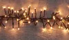A string of warm white LED lights on a dark wire, laid out horizontally on a wooden surface. Produktbild-Vorschau