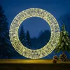 A lit wreath and a small Christmas tree on a wooden surface, with a snowy forest background. Produktbild-Vorschau