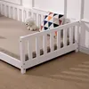 A close-up view of a white wooden child's bed with a guardrail, a mattress, and a decorative pillow. Náhľad obrázku produktu