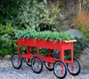 A red metal planter on wheels filled with green plants, set in a garden. Produktbild-Vorschau