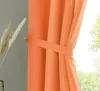 A close-up of an orange curtain held back by a tie-back. Produktbild-Vorschau