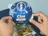 Hands holding a circular advent calendar for the Clue board game, which is open to reveal a game board. Produktbild-Vorschau