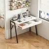 A modern white desk with black legs, featuring open drawers and items on top, placed in a room with wooden flooring and a window. Podgląd zdjęcia produktu