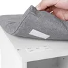 A hand is shown attaching a gray upholstered cushion to a white cabinet using velcro strips. Náhľad obrázku produktu