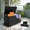 A black rattan storage box with its lid open, filled with cushions and towels, sits on a wooden deck. Voir les images du produit