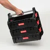 A hand holding a stack of three black Qbrick System Pro modular toolboxes. Náhľad obrázku produktu