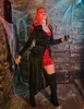A woman in a vampire costume holding a glass of red liquid in a dimly lit, stone-walled room decorated with cobwebs. Anteprima dell’immagine prodotto