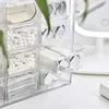 A clear acrylic organizer box with multiple compartments, filled with various small items like cotton swabs and pads. Produktbild-Vorschau