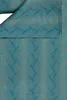 A close-up view of a teal-colored fabric with a wavy pattern in gold. Produktbild-Vorschau