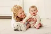 A mother and baby are playing on a rug with a stuffed bunny. Anteprima dell’immagine prodotto