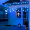Blue snowflake string lights are hung along the eaves of a house, illuminating the exterior. Náhled obrázku produktu