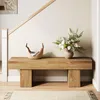 A wooden bench with a basket and a vase of flowers in a hallway next to a staircase. Voir les images du produit