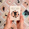 Hands holding an open box of 'Animal Spirit' tarot cards, with other cards spread out in the background. Voir les images du produit