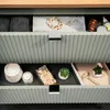 An open drawer of a vanity unit, showing various personal care items and accessories. Produktbild-Vorschau