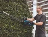 A man is trimming a hedge with a cordless hedge trimmer. Produktbild-Vorschau