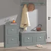 A hallway scene featuring a shoe cabinet, a shoe bench with storage, and a coat hanging on the wall. Náhľad obrázku produktu