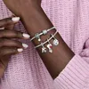 A close-up shot of a person's arm wearing two Pandora charm bracelets. Produktbild-Vorschau