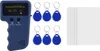 A handheld RFID writer, several RFID key fobs, and a stack of blank RFID cards are arranged on a white background. Podgląd zdjęcia produktu