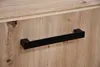 A close-up shot of a black handle on a wooden cabinet. Produktbild-Vorschau